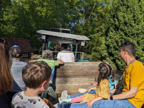 Menschen sitzen auf einem Trekkeranhänger.