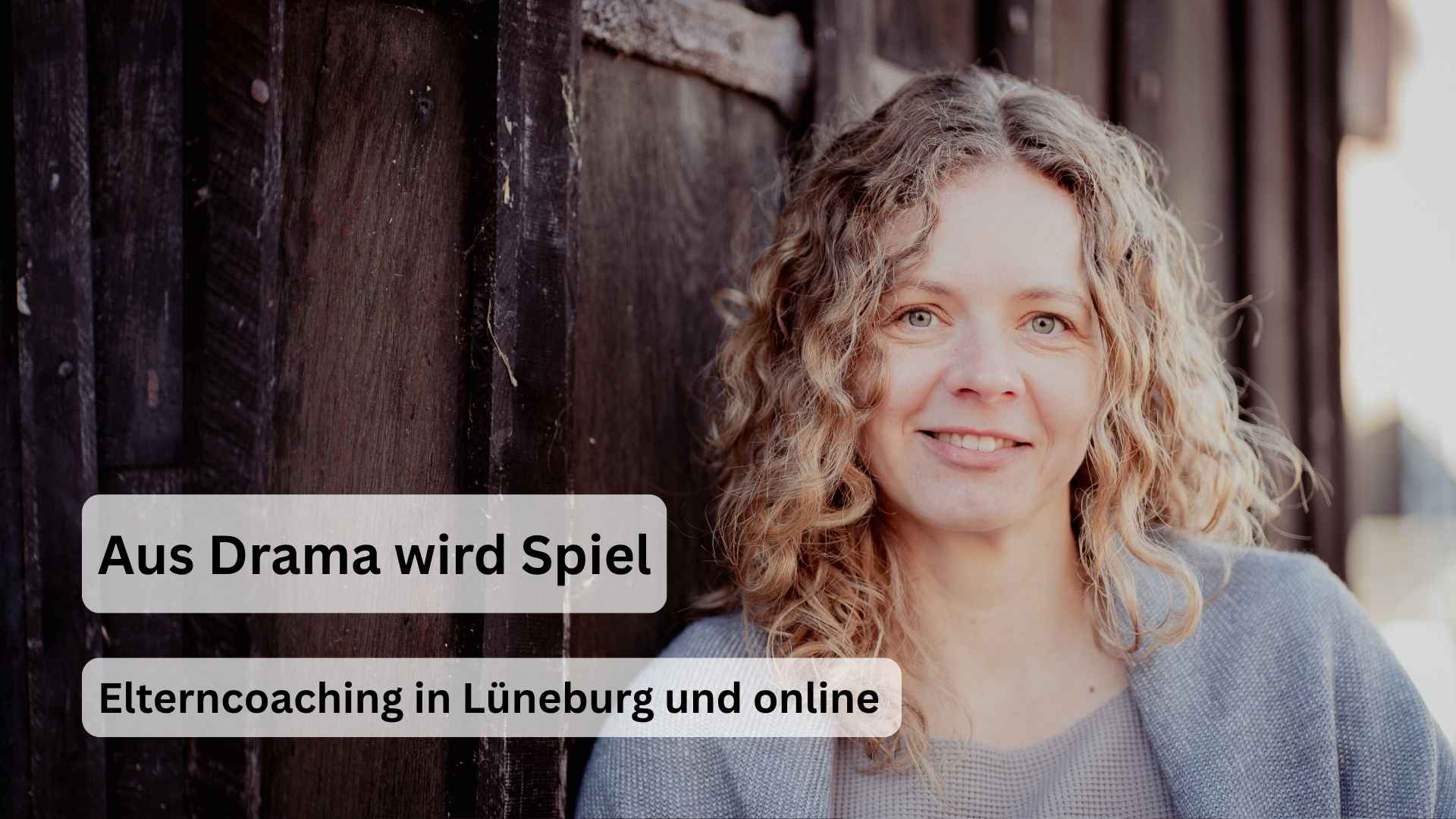 Frau mit lockigem Haar lehnt an einer Holzwand und blickt freundlich in die Kamera. Aufschrift: Aus Drama wird Spiel. Elterncoaching in Lüneburg und online.